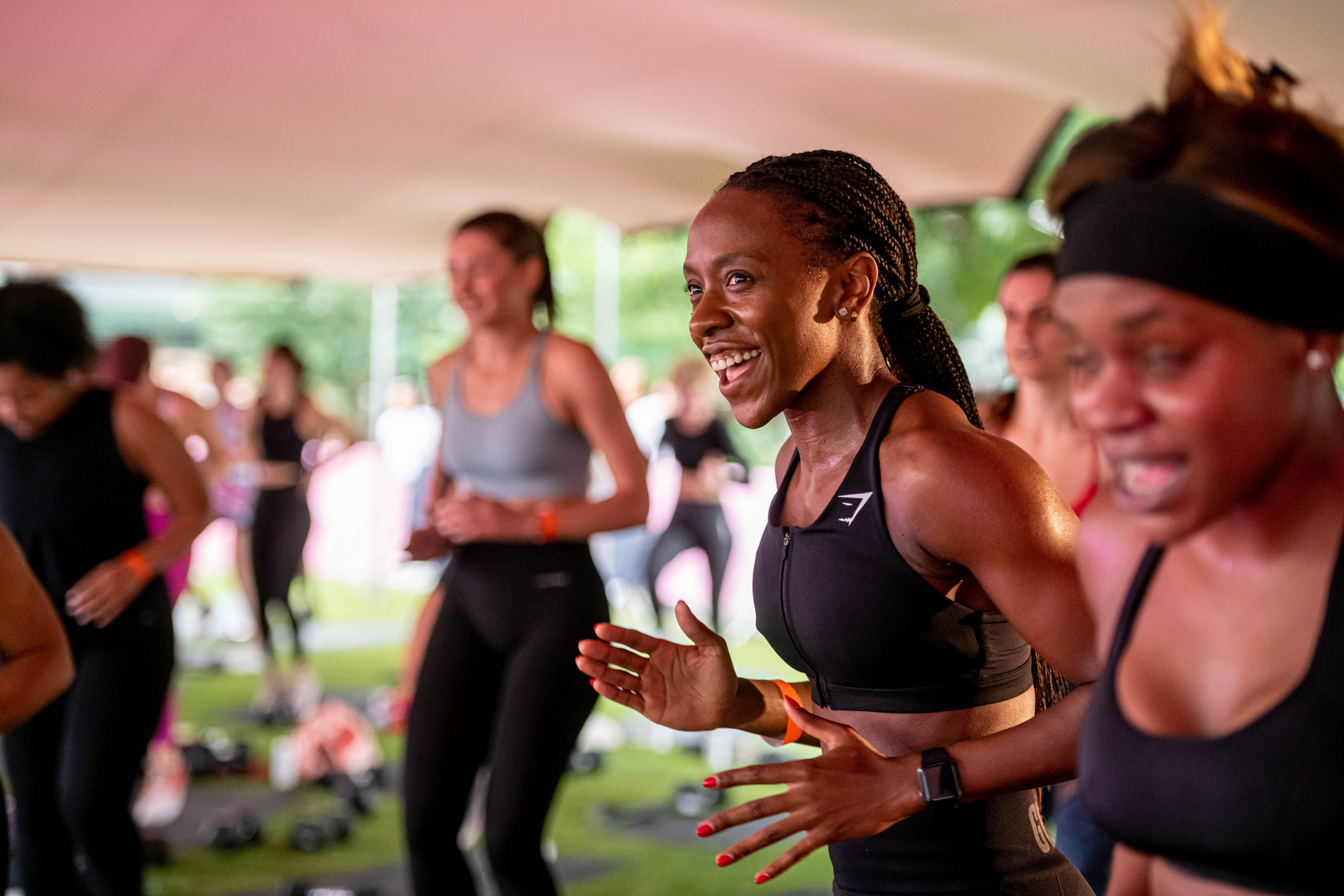 A woman wearing a black Gymshark top smiles during a busy work out session.